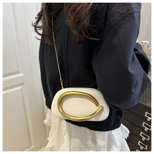 Detail of white leather crossbody bag with bold gold C-clasp and metal chain strap