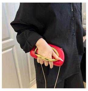 Detail of red acrylic round evening bag with large gold metal ring handle and chain