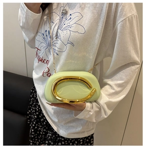Detail of pistachio green round acrylic bag with large gold metal handle and chain strap