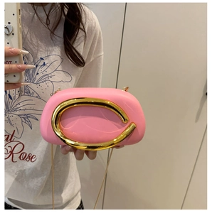 Pink acrylic clutch bag with a large gold circular handle and fine gold chain strap