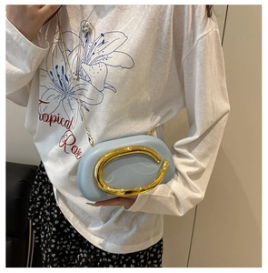 Close-up of light blue round acrylic clutch bag with a golden metal handle and chain