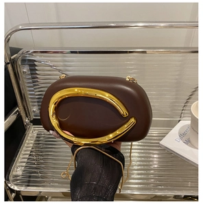 Chic dark brown oval clutch bag with large gold C-shaped metal handle and chain strap