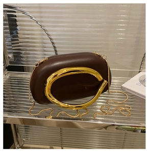Detail of round dark brown leather evening bag with golden circular metal handle and chain
