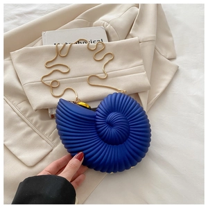 Detailed close-up of dark blue nautilus shell clutch bag with gold snake chain strap