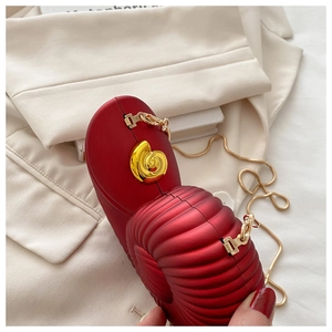 Detail of red snail-shaped clutch with gold shell clasp and sleek snake chain strap