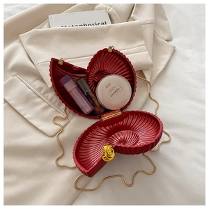 Detail view of red seashell evening bag with gold rose clasp and compact storage space