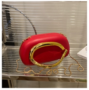 Detail of red acrylic evening bag with unique gold metal handle and snake chain strap