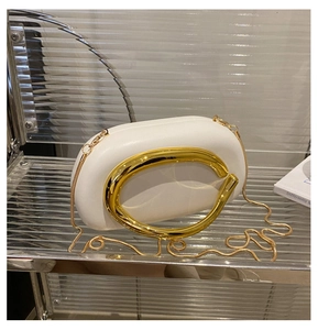 Detail of white acrylic round evening clutch with oversized gold metal circular handle