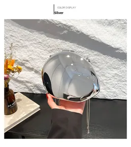 Detail of silver mirror acrylic oval clutch bag with metal chain shown in hand