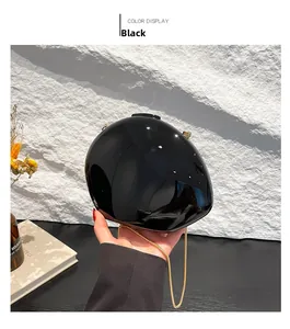 Detail view of the glossy black oval acrylic clutch bag with a gold metal chain strap