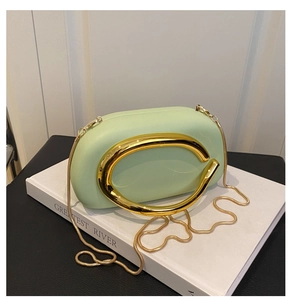 Detail of mint green acrylic evening bag featuring golden C-shaped handle and snake chain