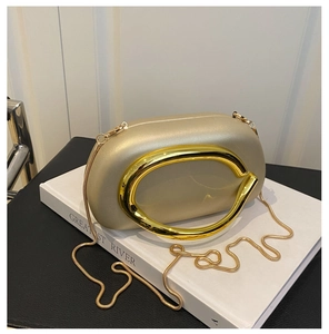 Detail of champagne gold hard shell evening bag with C-shaped handle and snake chain