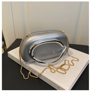 Detail of silver acrylic oval evening clutch bag with circular metal handle and gold chain