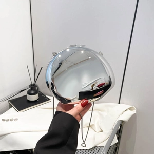 Silver mirror acrylic sphere evening bag with metal chain strap held by hand