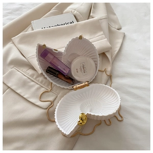 Close-up of shell-shaped evening bag interior holding lipstick and cosmetics with chain