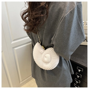 Chic white conch shell crossbody bag with gold chain strap worn by a female model