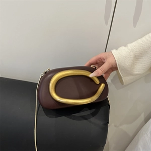 Deep wine red leather crossbody bag featuring a matte gold C-shaped handle and snake chain
