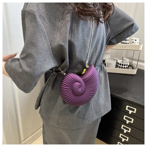 Detail of the purple seashell-shaped crossbody bag with a slim gold chain and spiral texture