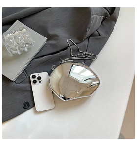 Macro shot of silver mirrored shell clutch bag with metallic chain on a stylish suit