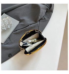 Detail view of gold oval clutch bag interior showing space for phone and small cosmetics