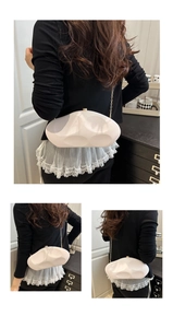 Detail of white sculptural acrylic clutch with organic curves and golden chain strap