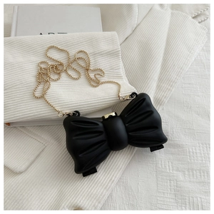 Detail der mattschwarzen Clutch in Schleifenform mit elegantem goldener Kette