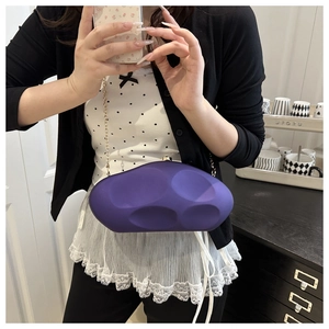 Close-up of purple geometric acrylic clutch bag with gold chain strap on female model