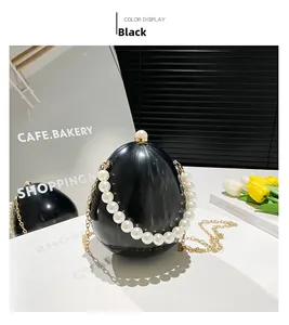 Détail de la pochette œuf en acrylique noir avec anse perle et chaîne dorée
