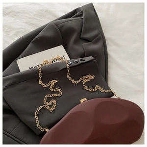 Detailed view of burgundy geometric stone clutch with fine gold chain and metallic clasp