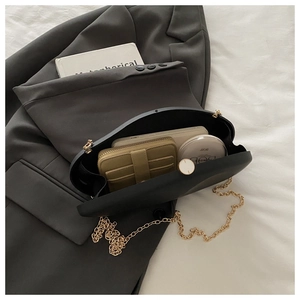 Macro view of black evening clutch showing interior capacity with golden chain strap