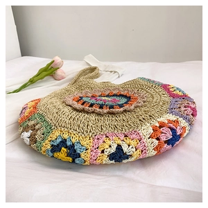 Détail de motifs au crochet bohème colorés sur un sac de plage rond en paille