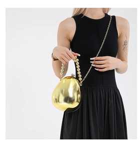 Détail de la pochette œuf en acrylique doré avec poignée perle et chaîne sur robe noire