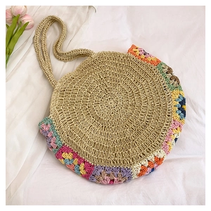 Détail de motifs floraux au crochet colorés sur un sac de plage en paille tressée