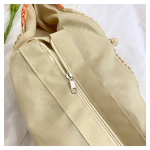 Détail d'un sac en paille tressée avec doublure beige et fermeture éclair en métal argenté