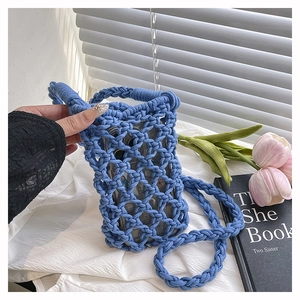 Gros plan du sac de téléphone en macramé bleu avec texture maille et bandoulière assortie