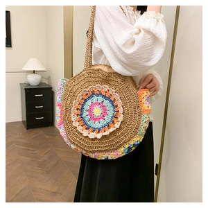 Gros plan détaillé du sac à bandoulière en paille avec des motifs floraux au crochet colorés