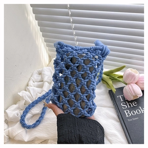 Gros plan du sac de téléphone en crochet bleu tenu à la main avec maille évidée