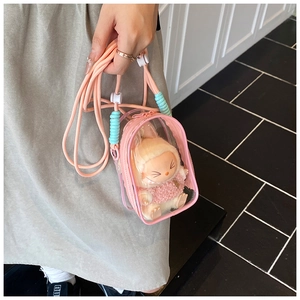 Detail of pink transparent PVC jelly bag with plush doll inside and woven shoulder strap