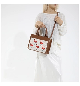 Détail de la broderie flamant sur un sac bandoulière en cuir avec poignées