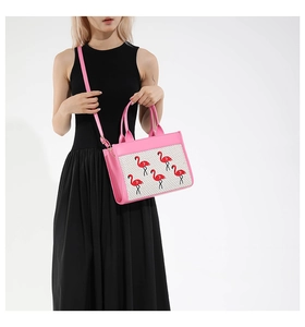 Détail d'un sac à bandoulière rose avec panneau tissé et broderie flamant rose sur modèle