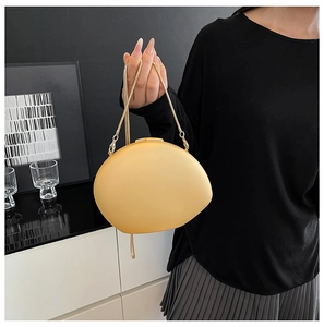 Detail view of mustard yellow pebble-shaped acrylic evening clutch with golden chain strap