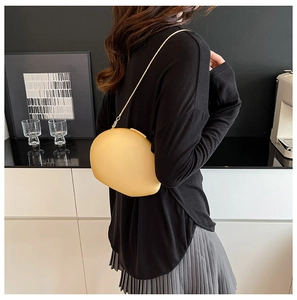 Close-up of beige acrylic shell bag with gold chain strap on model in modern setting