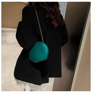 Detail of dark green egg-shaped acrylic evening clutch with fine gold chain strap