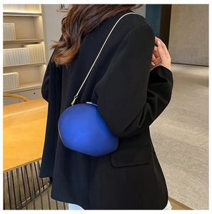 Blue irregular acrylic crossbody bag with gold chain strap shown on a black suit