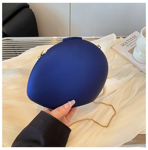 Detail of navy blue oval acrylic evening bag with gold chain and matte finish texture