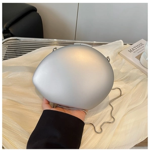 Close-up of matte silver egg-shaped acrylic clutch bag with thin metal snake chain