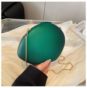 Detail of matte emerald green egg-shaped clutch bag with delicate gold chain strap