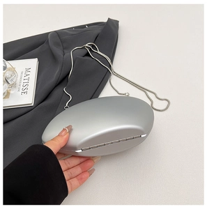 Close-up of matte silver egg-shaped clutch bag with delicate snake chain strap