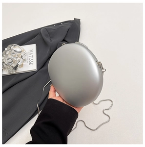 Close-up of matte silver oval hard shell evening bag with elegant metal snake chain