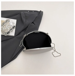 Silver oval evening bag featuring a hard shell, black lining, and fine metal chain strap